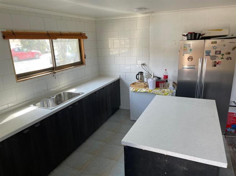 Cocina lineal con isla y cubierta de cuarzo blanco